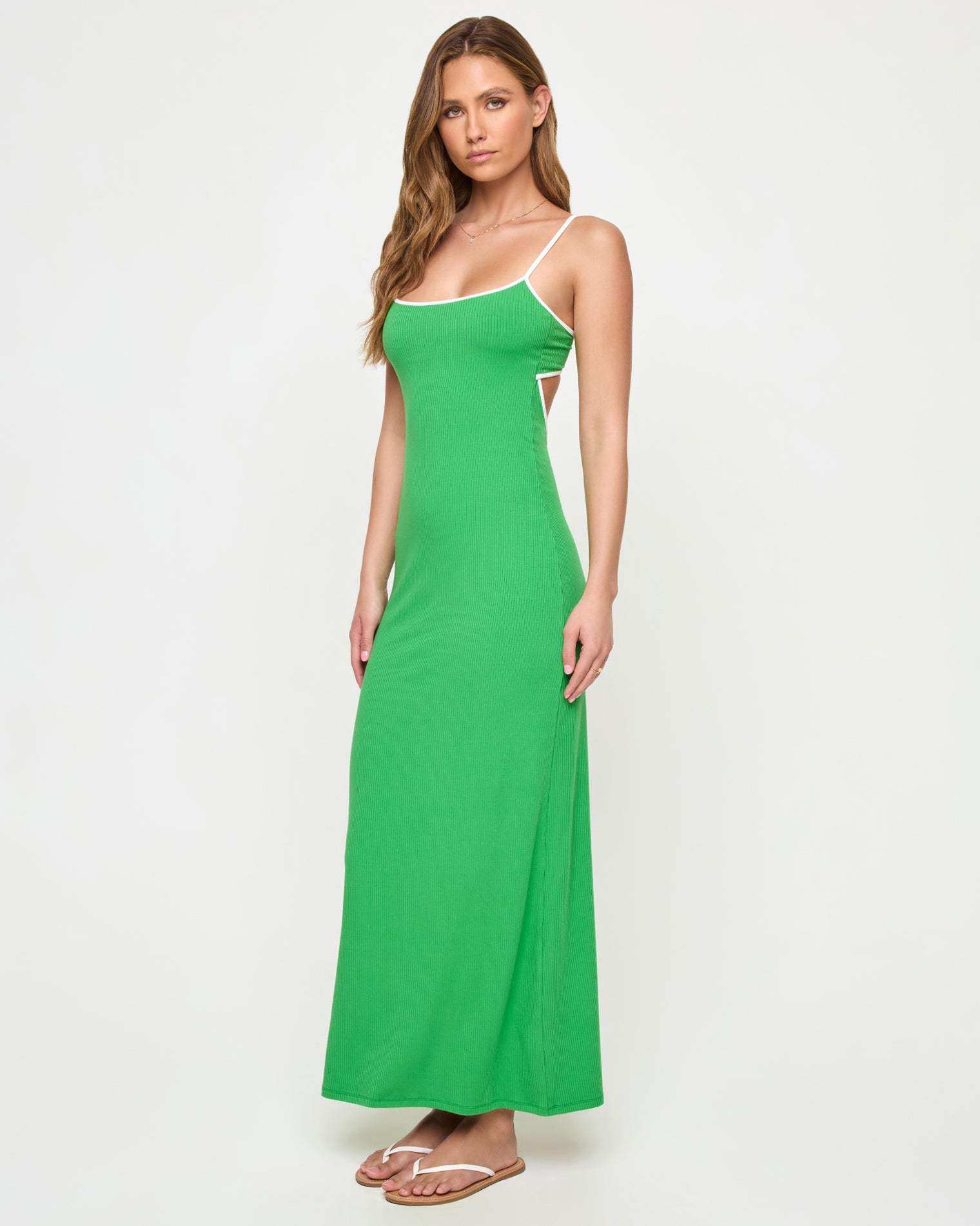 Jordana Dress - Clover-Cream Side view of a model wearing the LSPACE Jordana Dress in clover-cream, highlighting the open back cutout detail and cream contrast trim against the clover green ribbed fabric.