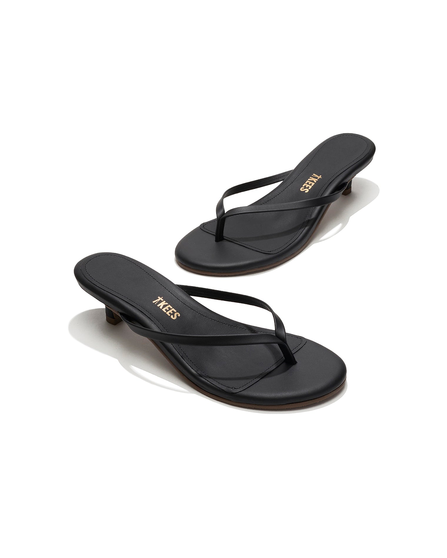 TKEES Julia Kitten Heel - Sable Angled view of both black sable leather TKEES Julia Kitten Heel thong sandals with TKEES logo.