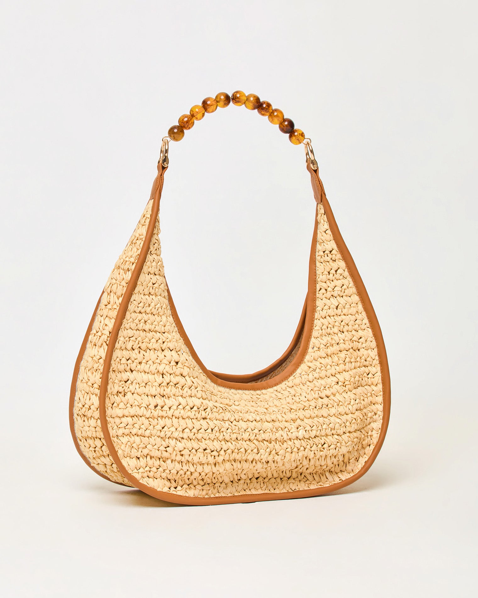 Mira Mar Bag - Natural Angled side view of the natural Mira Mar Bag showing the raffia weave and brown leather trim detail.