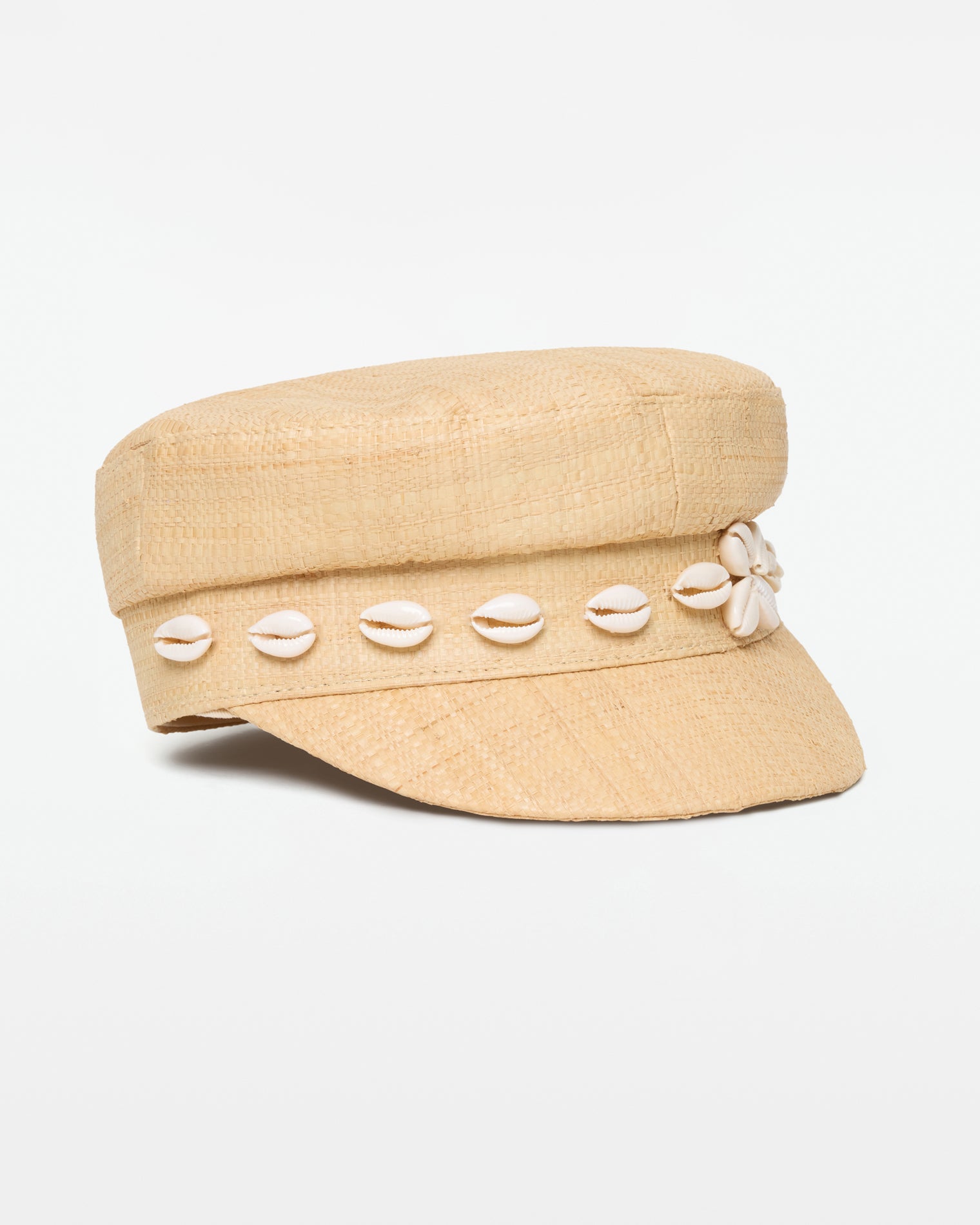 Alfama Cap - Natural Off-model side view of the Alfama Cap in natural, a woven raffia baker boy cap with a cowrie shell band trim, on a white background.
