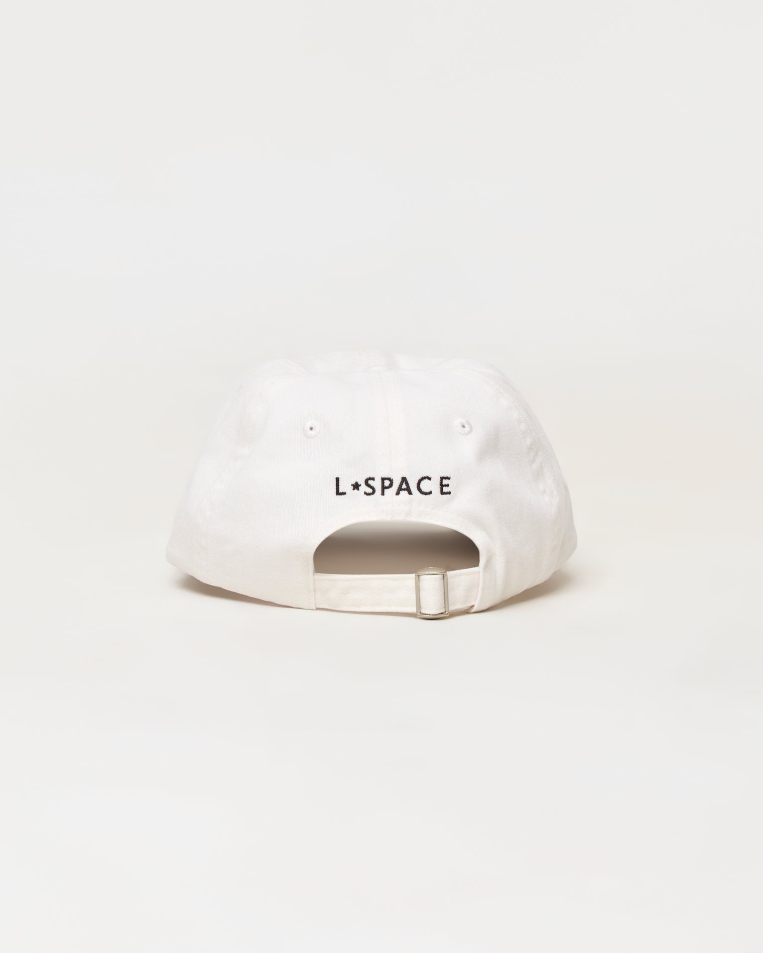 Buns Out Hat - Everyday A white baseball cap shown from the back, featuring the black text 'L*SPACE' printed across the center. The cap has a curved brim, eyelets, and an adjustable snapback strap, photographed against a seamless white background.