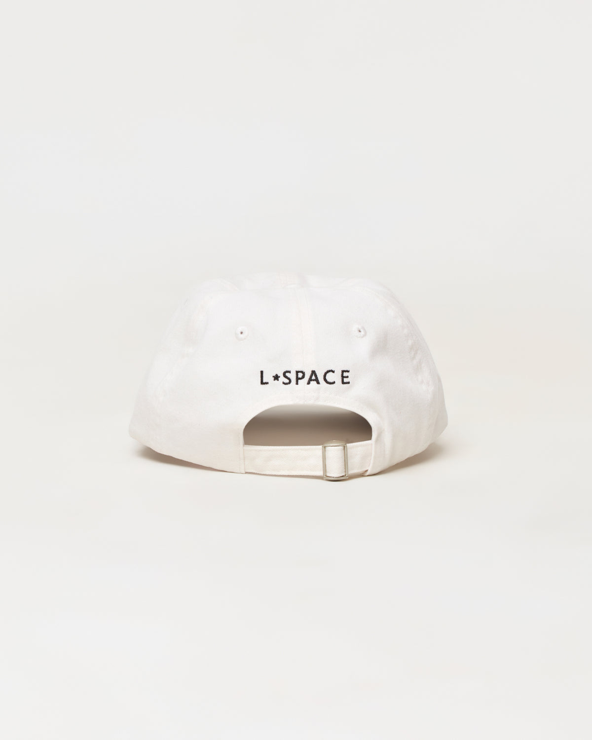 Buns Out Hat - Everyday A white baseball cap shown from the back, featuring the black text 'L*SPACE' printed across the center. The cap has a curved brim, eyelets, and an adjustable snapback strap, photographed against a seamless white background.
