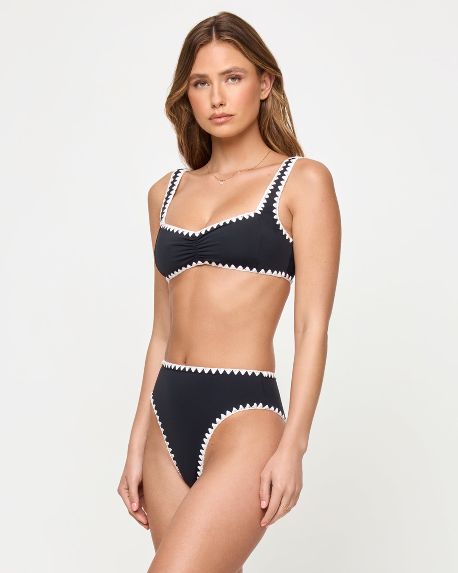 Effie Bikini Top - Black-Cream side view of woman wearing a black bikini with white trim on a plain background