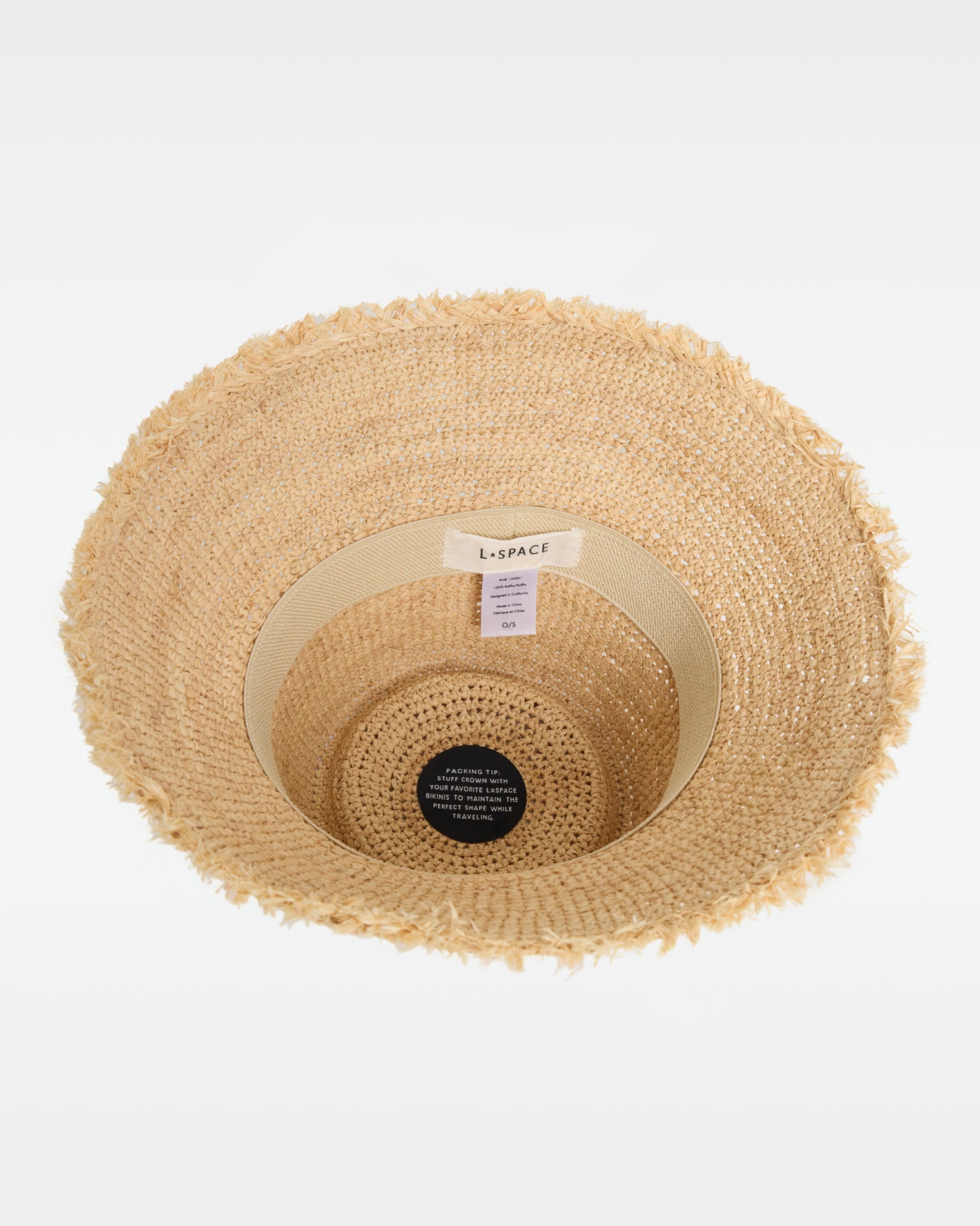 Paco Bucket Hat - Natural Top-down interior view of the Paco Bucket Hat in natural showing the LSPACE branding label and packing tip tag, with the frayed brim visible around the edge.