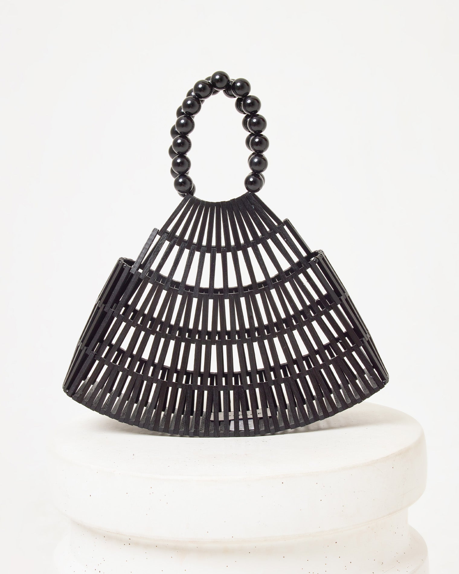 Starlight Bag - Black Off-model image of the Starlight Bag in black, a bamboo slat cage-style structured bag with a black beaded handle, on a white pedestal.