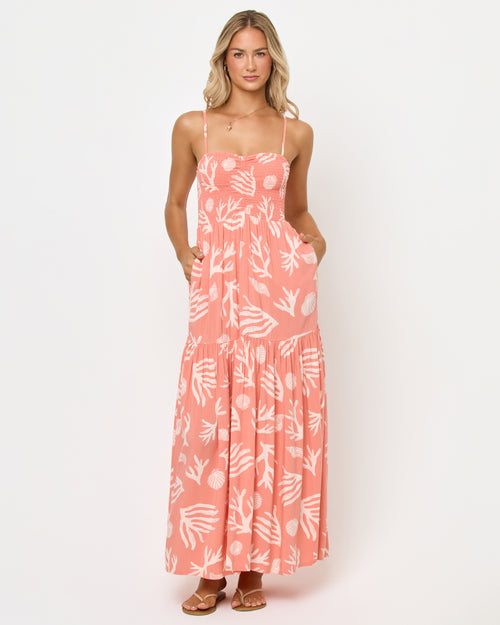 Front view of a model wearing the LSPACE Mallorca Dress in Shell Or High Water, highlighting the smocked sweetheart bodice and flowing tiered maxi skirt in a coral shell and reef print.