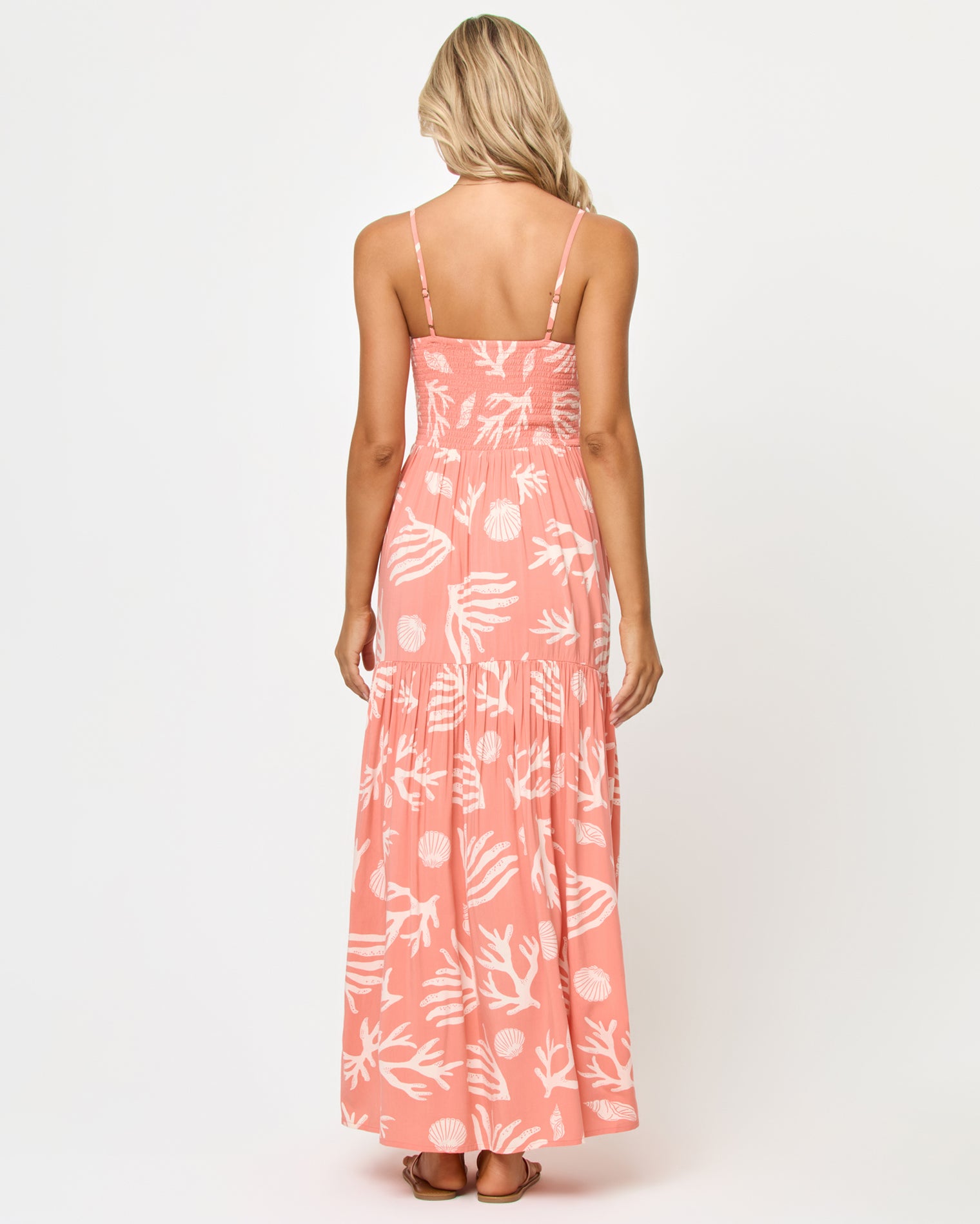 Mallorca Dress - Shell Or High Water Back view of a model wearing the LSPACE Mallorca Dress in Shell Or High Water, showing the smocked back bodice and tiered maxi skirt in the coral shell and reef print.