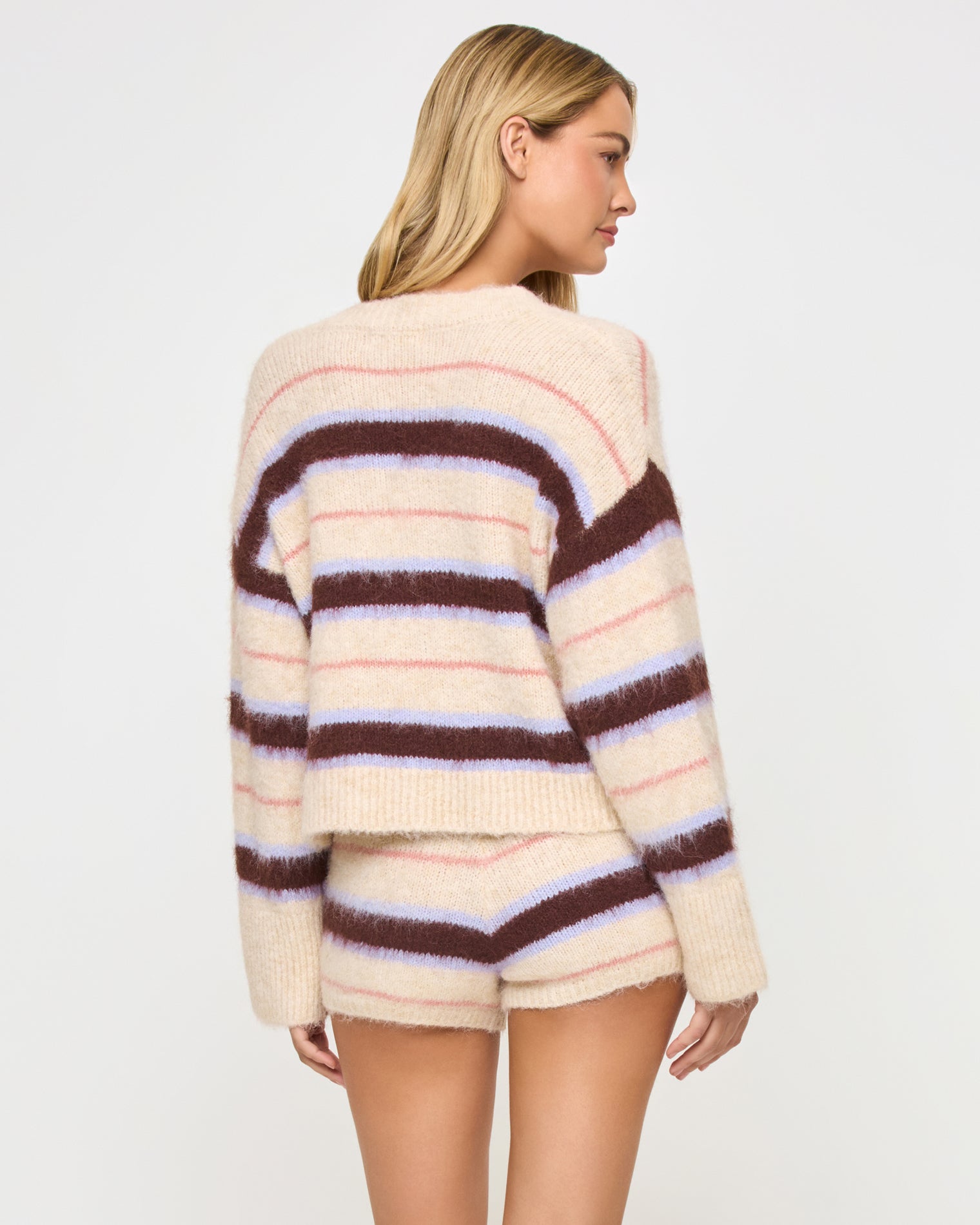 Montauk Cardigan - Prep School Stripe Back view of a model wearing the LSPACE Montauk Cardigan in prep school stripe, a cropped oversized button-front cardigan in a soft eyelash knit with horizontal cream, dark brown, lavender, and pink stripes, styled with the matching Montauk Short.