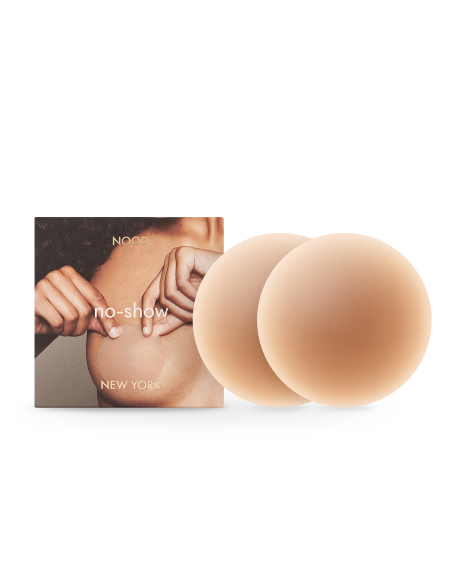 NOOD No Show Adhesive Nipple Covers - Tan Off-model image of the NOOD No Show Adhesive Nipple Covers in tan with the NOOD branded packaging box.