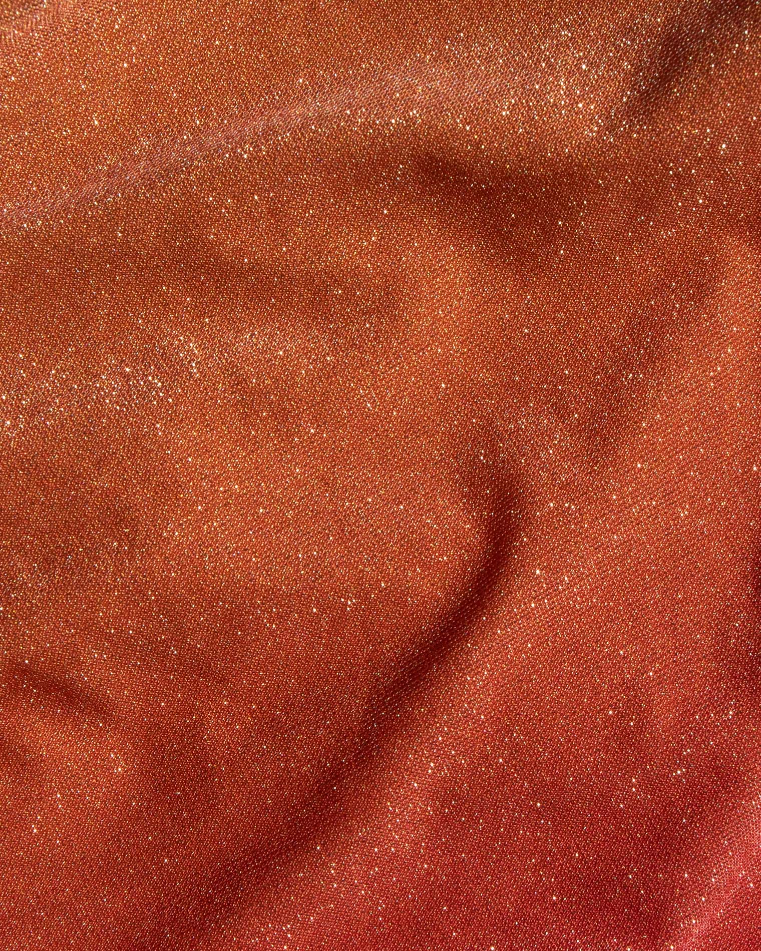Banning Bikini Bottom - Ocaso A close-up of a textured fabric with a fine glittery finish, showing a warm coppery-brown color with subtle folds and shimmer.