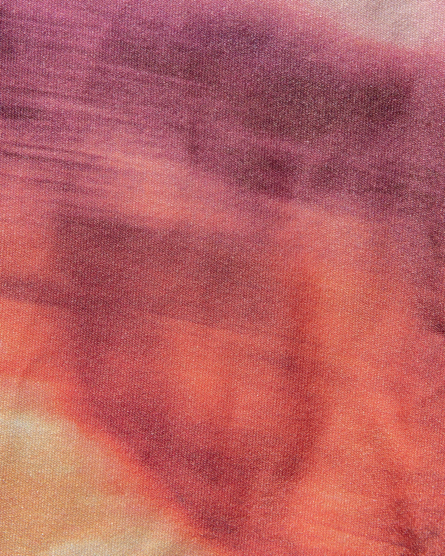Avalon Bikini Top - Island Hopper Close-up of a fabric with a tie-dye pattern in shades of purple, orange, and pink.