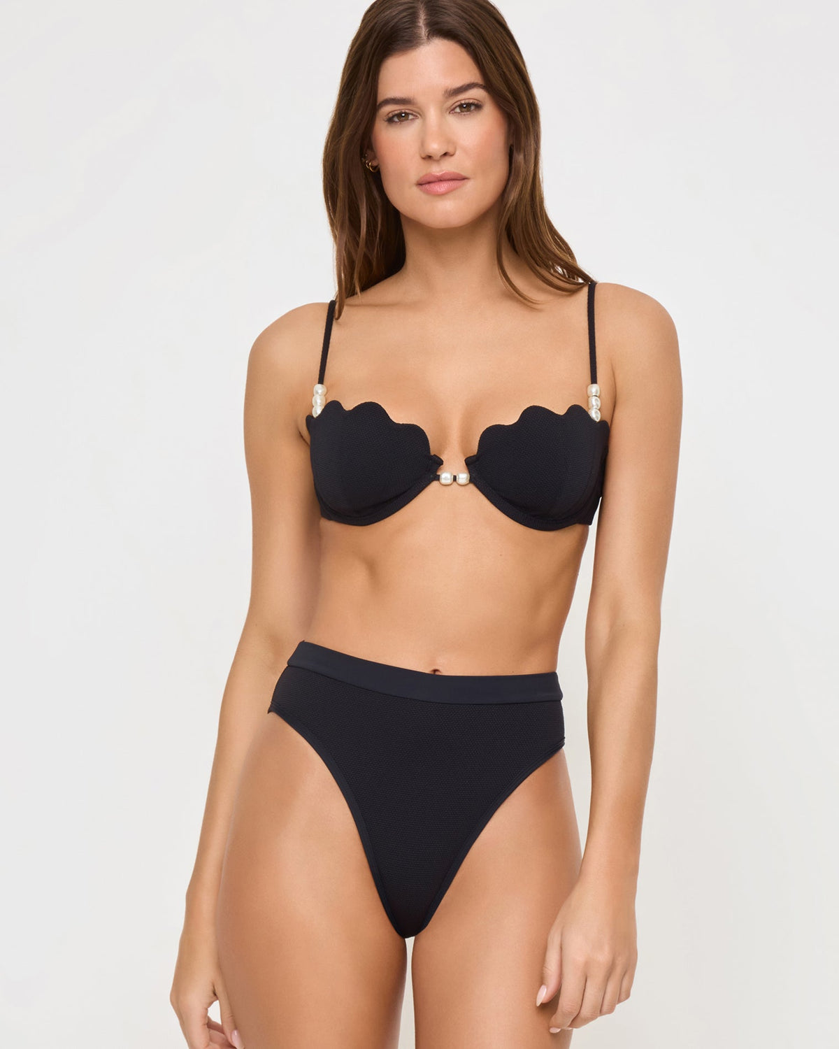 Sunrise Shell Bikini Top - Black Front view of a model wearing the LSPACE black Sunrise Shell Bikini Top, a scalloped underwire style with pearl hardware, paired with a black high-waist Frenchi Bikini Bottom.