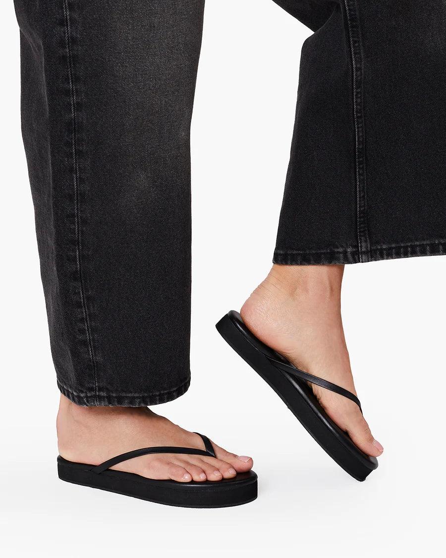 TKEES Lily Platform Sandals - Black Side view of a model wearing the black TKEES Lily Platform Sandals with dark jeans.