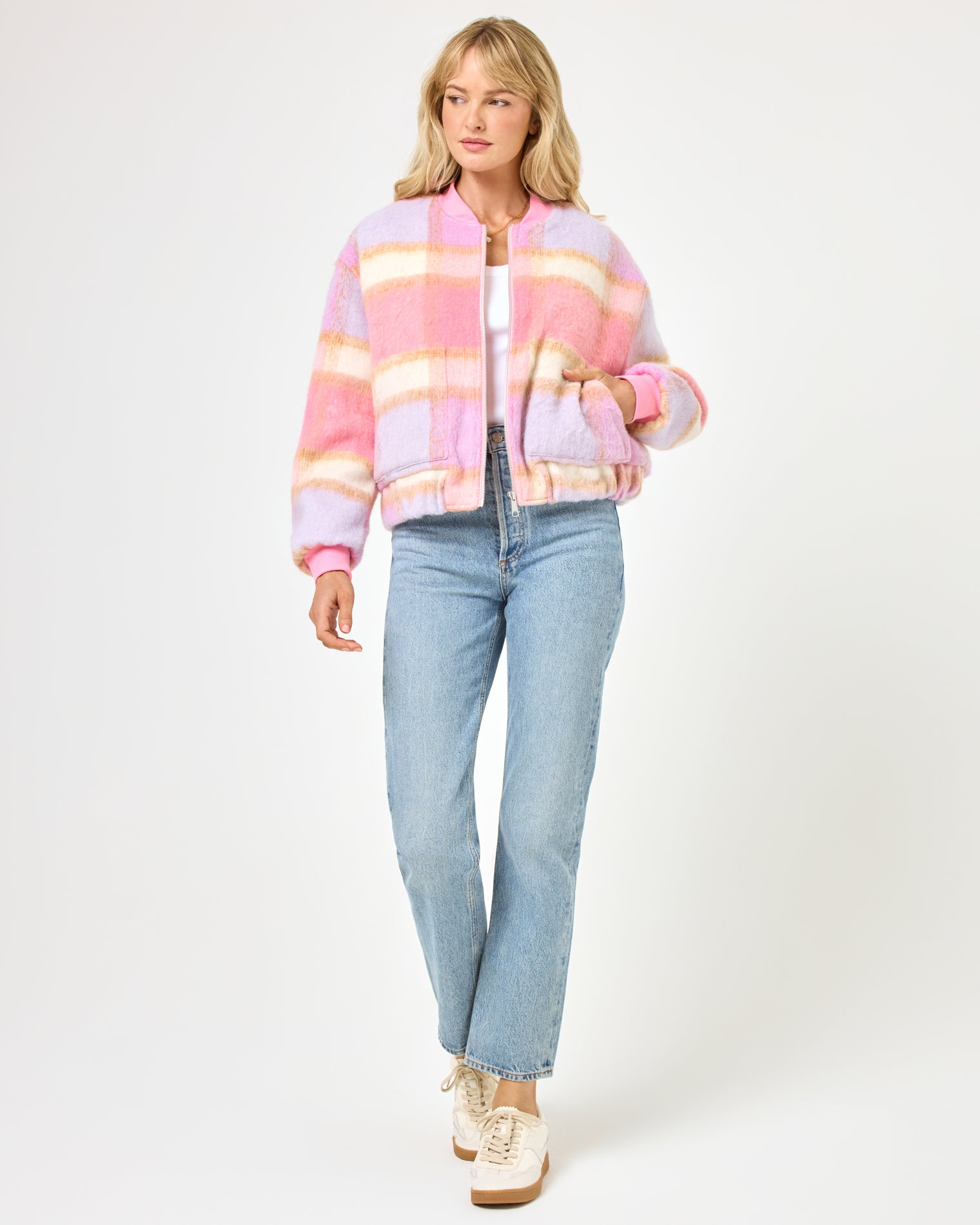 Quinn Jacket - Point Dume Plaid Front view of a model wearing the LSPACE Quinn Jacket in point dume plaid, a cozy oversized bomber jacket with a pink, lavender, and cream plaid pattern, styled with wide-leg jeans and sneakers.