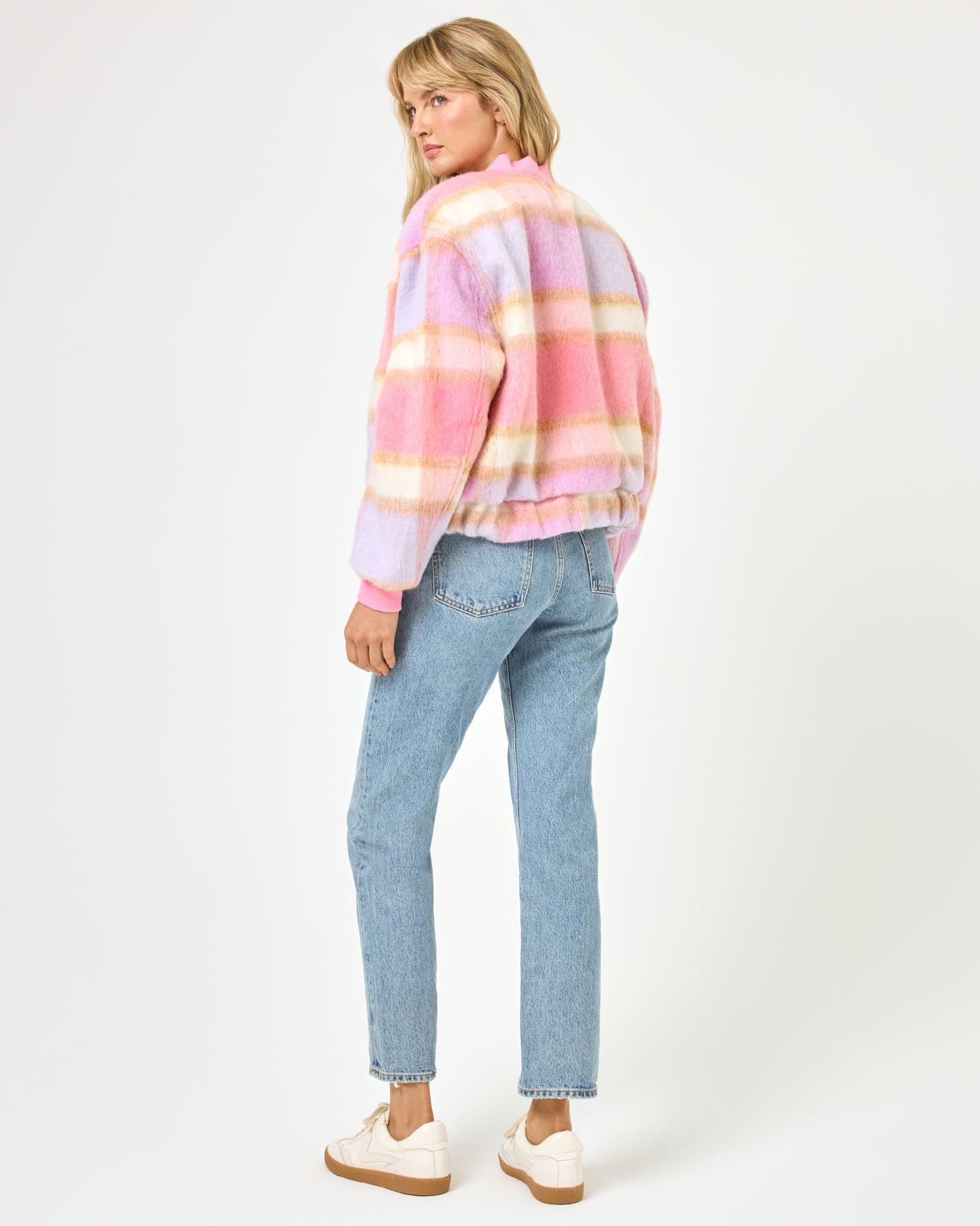 Quinn Jacket - Point Dume Plaid Back view of a model wearing the LSPACE Quinn Jacket in point dume plaid, showing the pink, lavender, and cream fuzzy plaid pattern across the bomber jacket back, styled with wide-leg jeans.