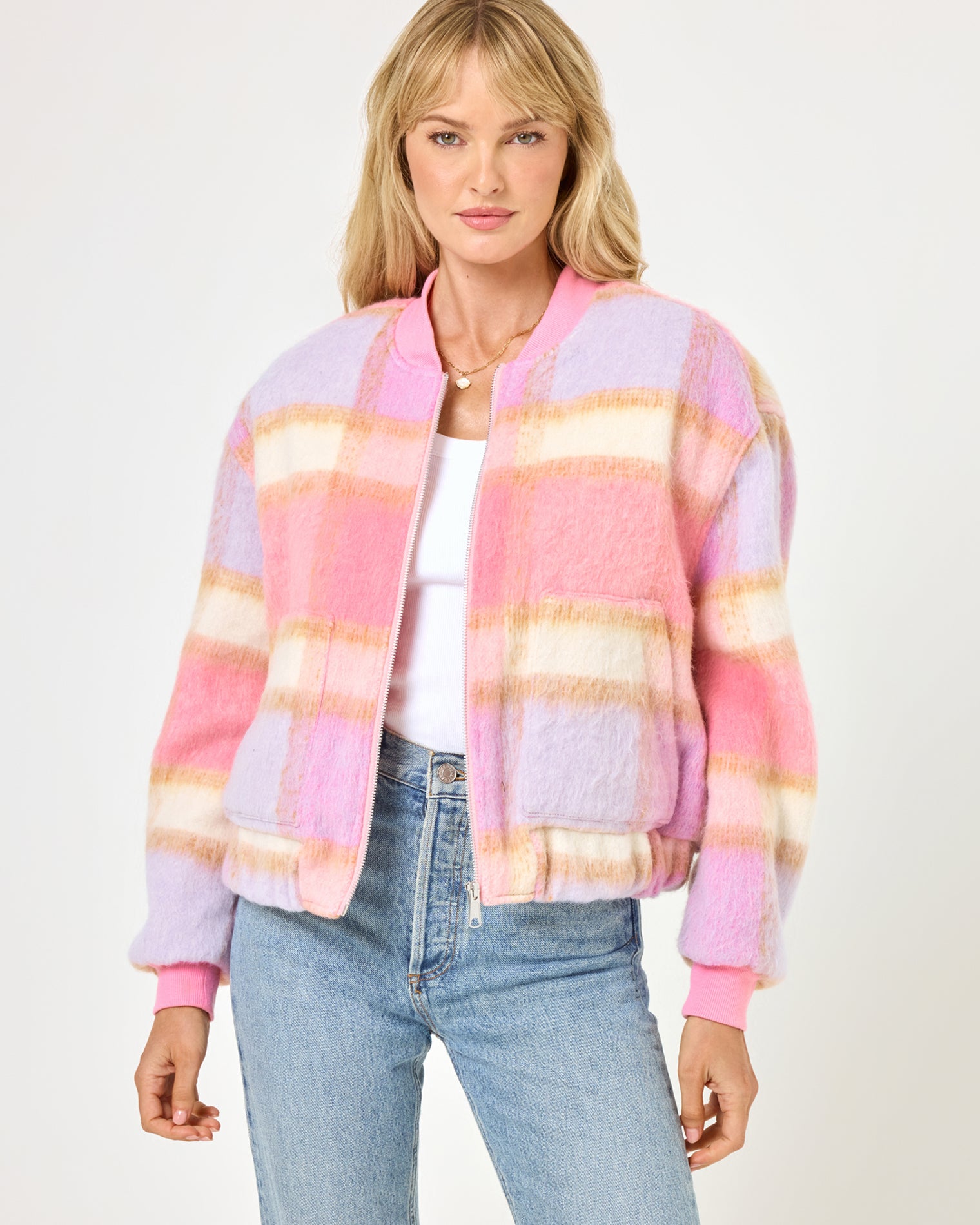 Quinn Jacket - Point Dume Plaid Close-up front view of a model wearing the LSPACE Quinn Jacket in point dume plaid, featuring a soft fuzzy plaid pattern in pink, lavender, and cream with a zip-up bomber silhouette and ribbed cuffs.