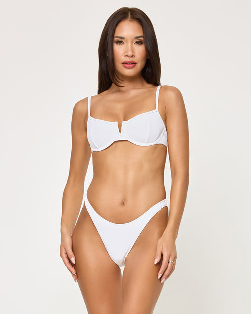 Front view of a model wearing the LSPACE white Donnie Bikini Bottom, a low-rise cheeky style, paired with a matching white underwire Hunter Bikini Top