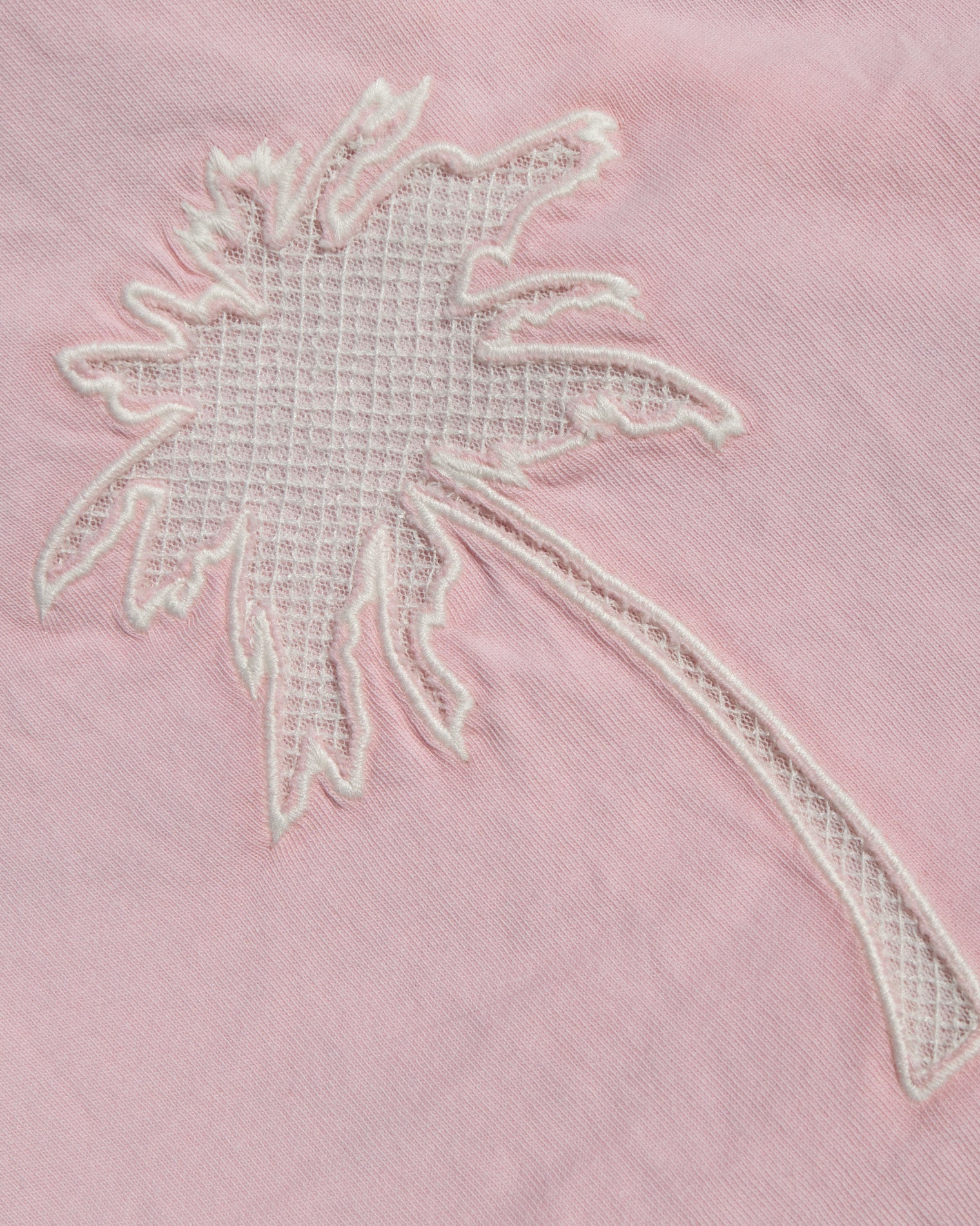 Core Top - Rosewater A close-up of a light pink fabric featuring a white embroidered palm tree motif.