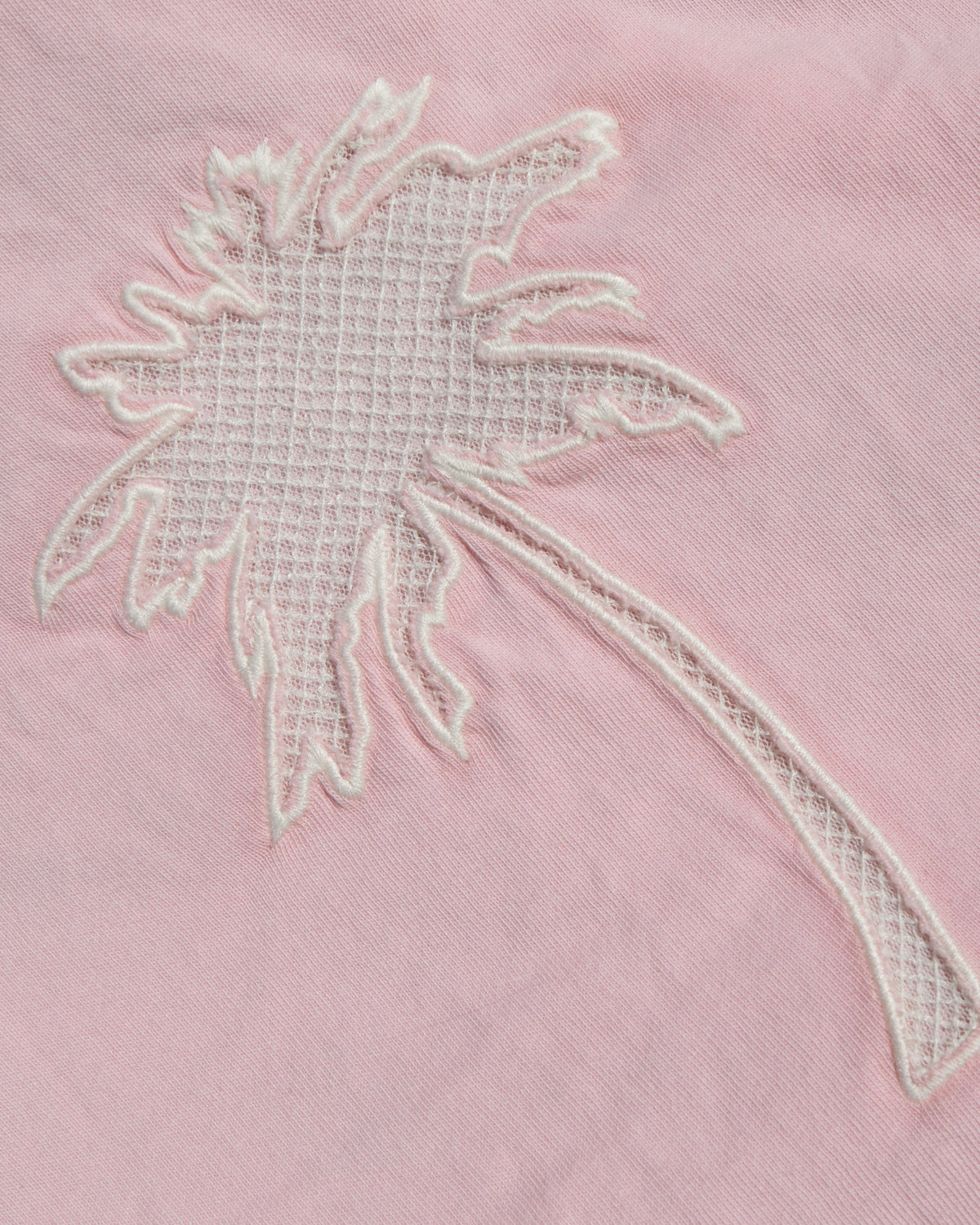 Core Top - Rosewater A close-up of a light pink fabric featuring a white embroidered palm tree motif.