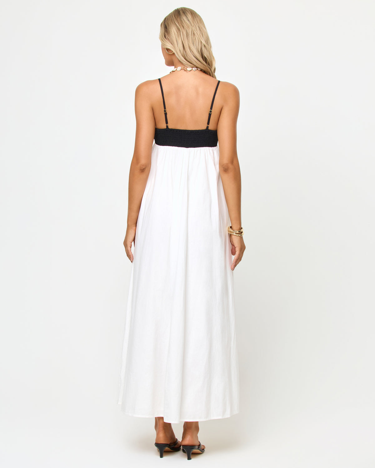 Raveena Dress - Black-Cream Back view of a model wearing the LSPACE Raveena Dress in black-cream, showing the adjustable spaghetti straps against the black bodice and the full flowing cream maxi skirt.