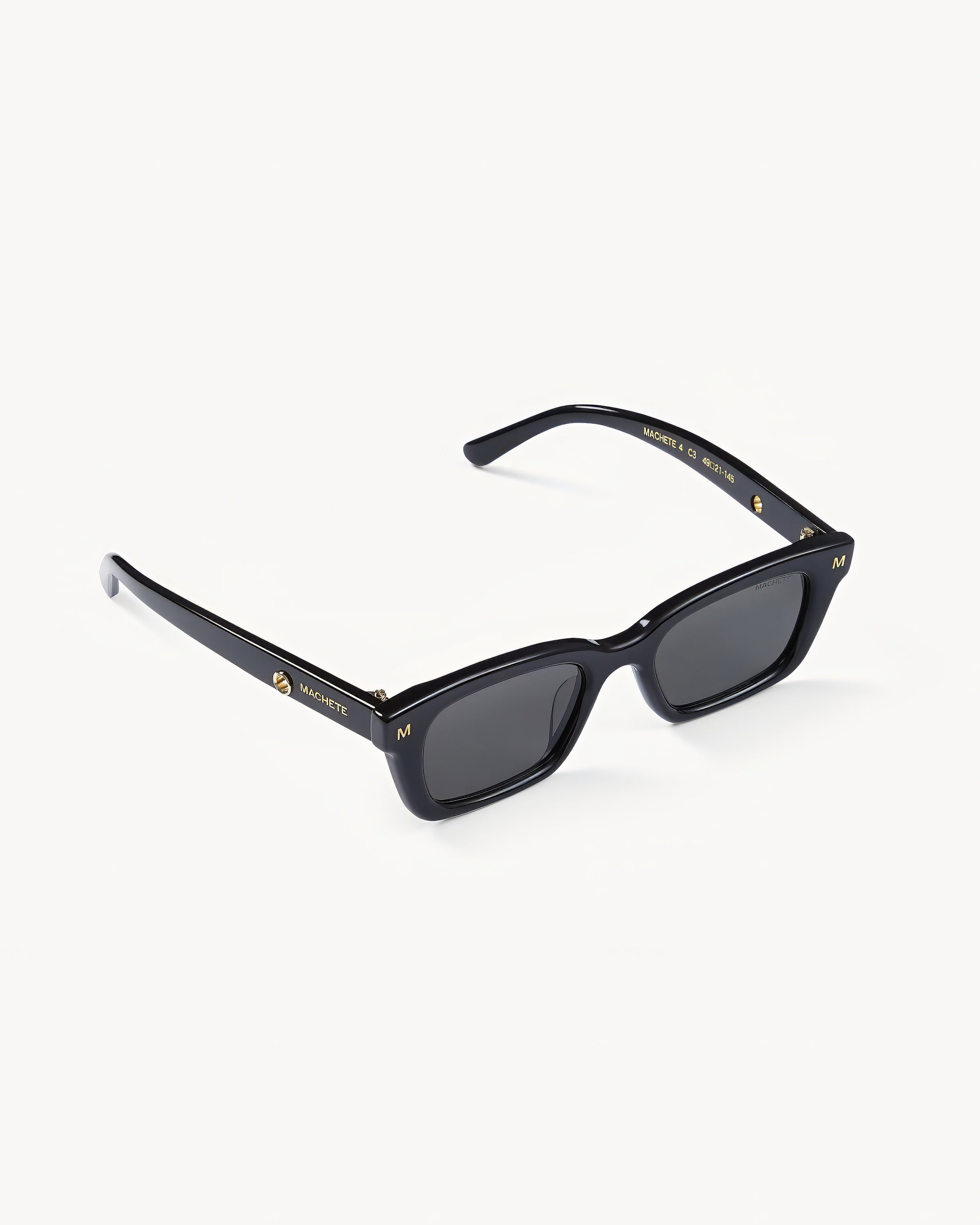 Machete Ruby Sunglasses - Black Off-model angled view of the Machete Ruby Sunglasses in black showing the rectangular frame and dark grey lenses.