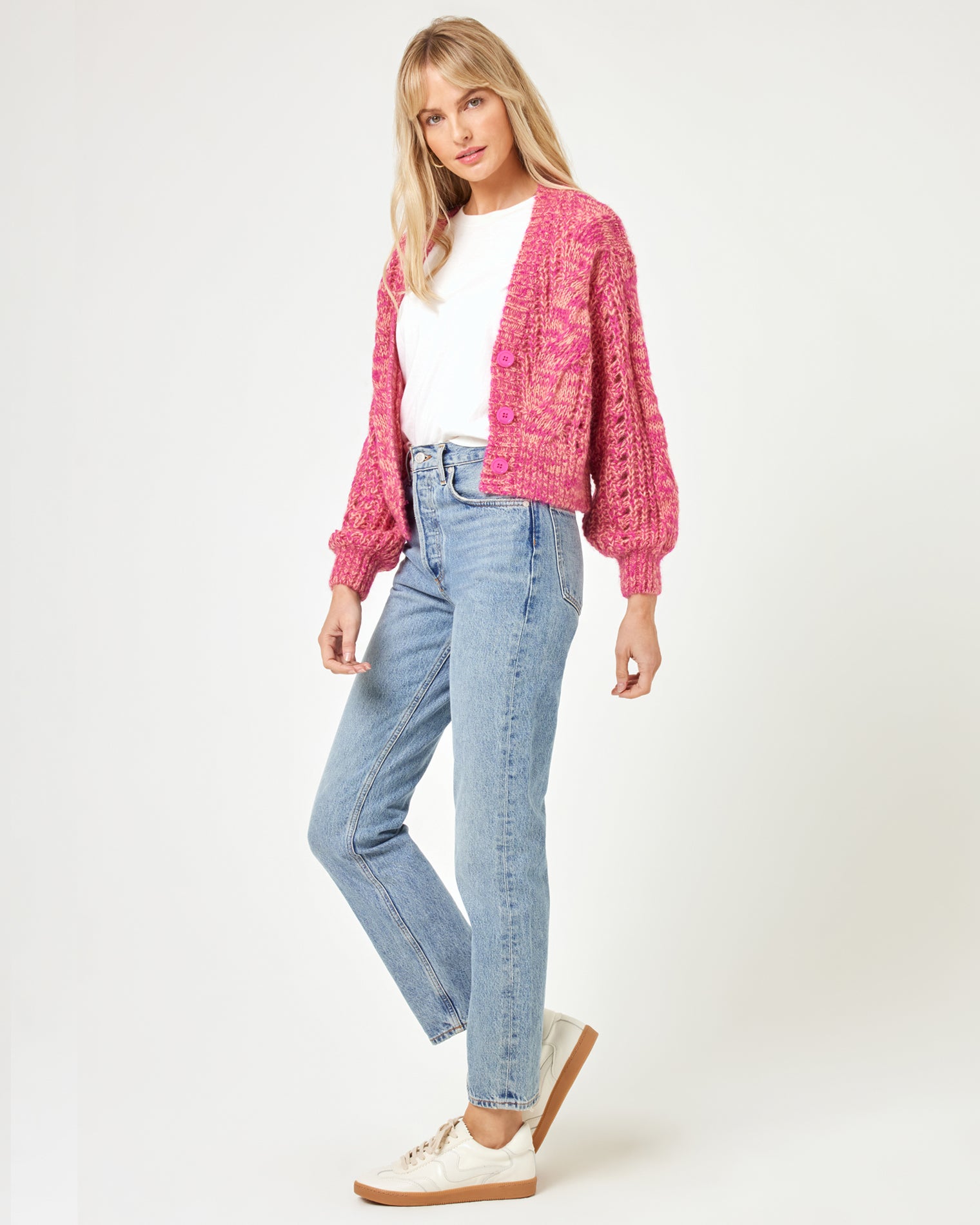 Strawberry Fields Cardigan - Strawberry Marl Side view of a model wearing the LSPACE Strawberry Fields Cardigan in strawberry marl, showing the relaxed cable-knit silhouette styled with jeans and sneakers on a white background.
