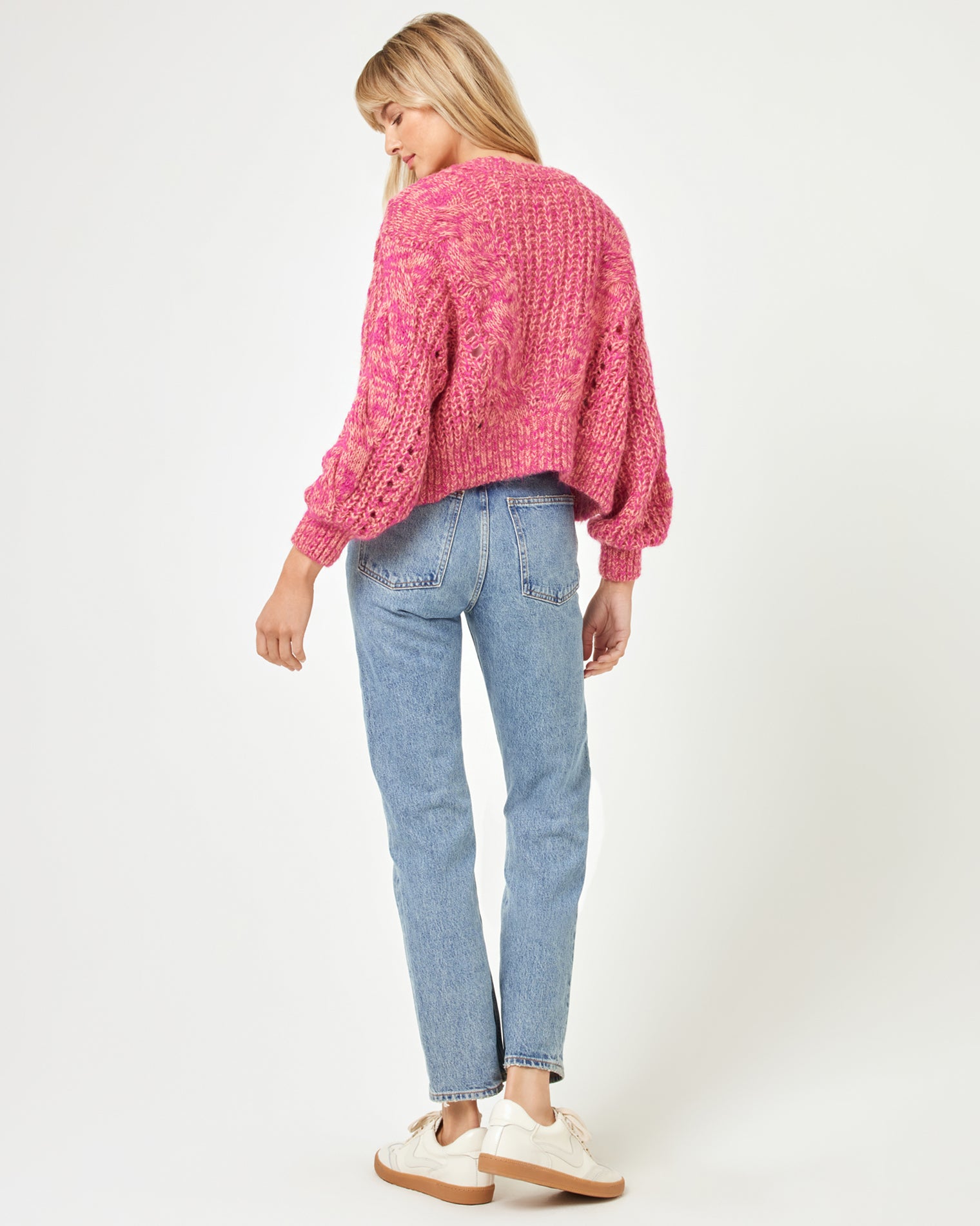 Strawberry Fields Cardigan - Strawberry Marl Back view of a model wearing the LSPACE Strawberry Fields Cardigan in strawberry marl, showing the pink cable-knit back and long sleeves on a white background.