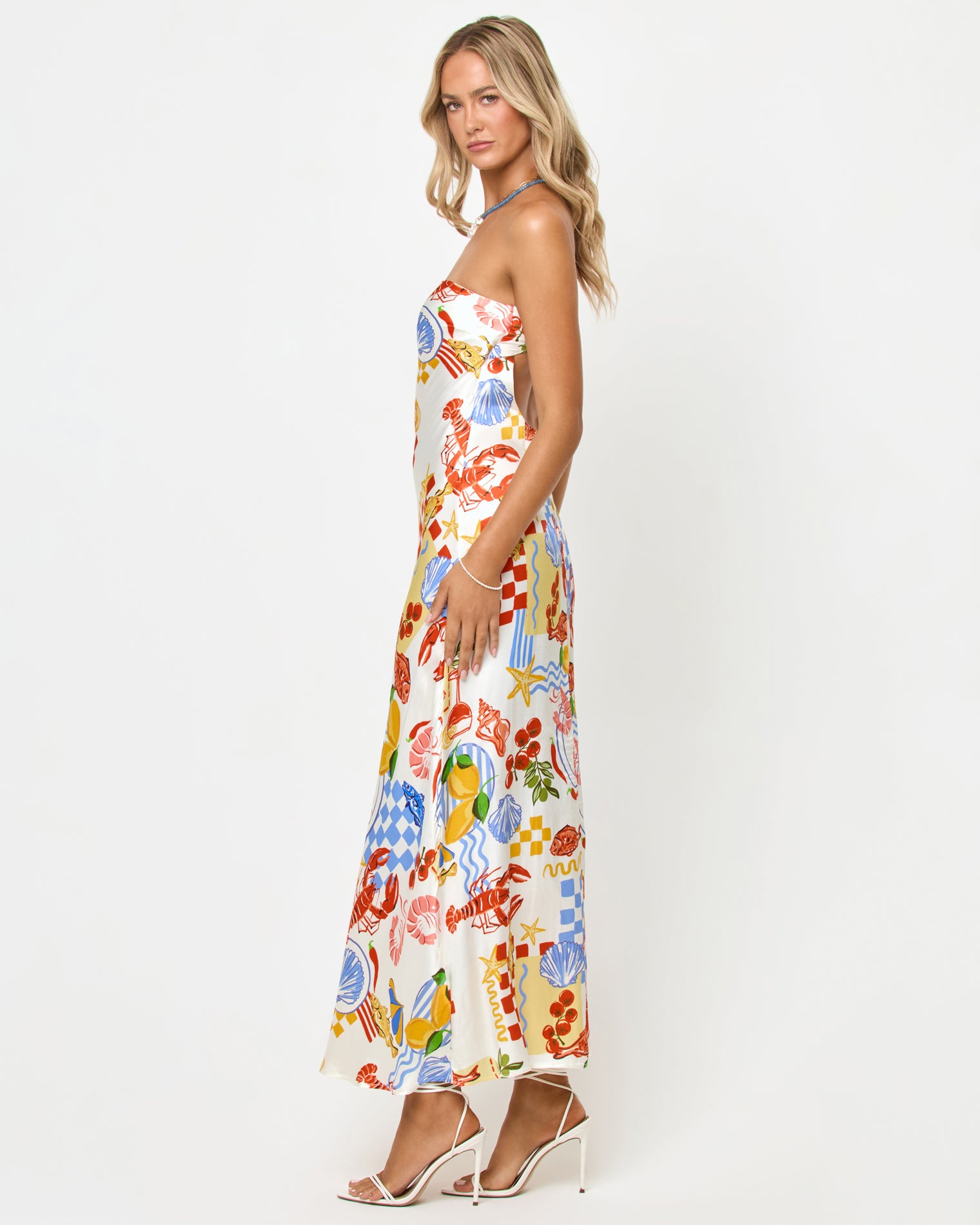 Spring In Love Dress - Seaside Soiree Side view of a model wearing the LSPACE Spring In Love Dress in seaside soiree, showing the full length and satin silhouette of the strapless maxi dress with seaside print.
