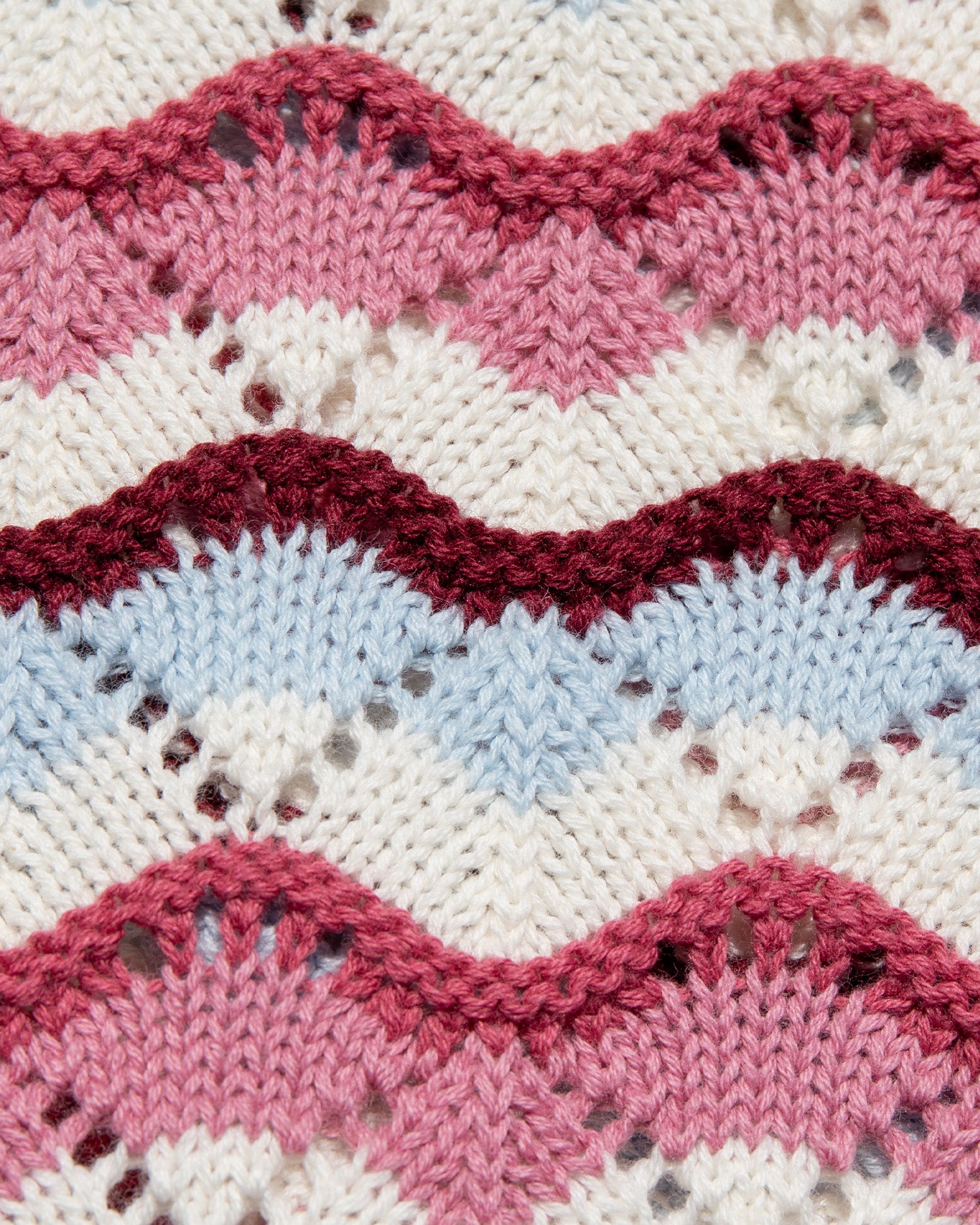 Sunchaser Dress - Sand In Hand Close-up detail of the LSPACE sand in hand Sunchaser Dress crochet knit fabric, showing the wavy stripe texture in pink, burgundy, blue, and cream.