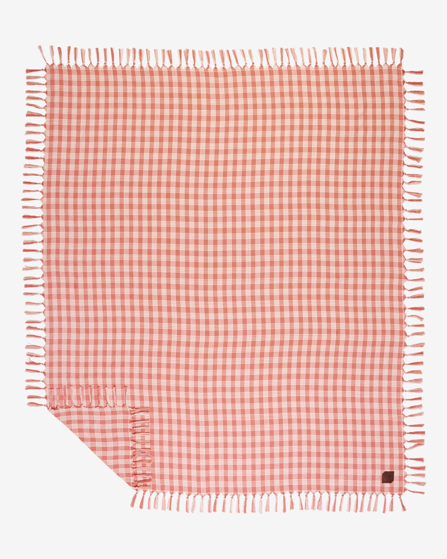 Slowtide Palaka Lightweight Beach Blanket - Guava Flat lay of the Slowtide Palaka Lightweight Beach Blanket in guava, showing a pink gingham check pattern with fringe on all edges.