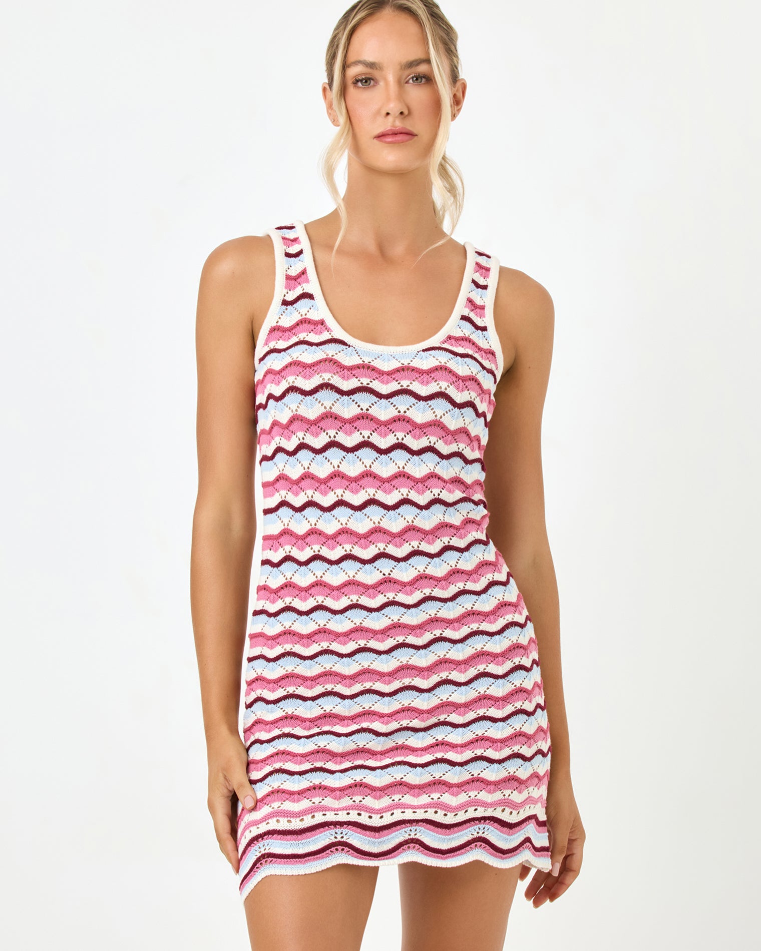 Sunchaser Dress - Sand In Hand Close-up front view of a model wearing the LSPACE sand in hand Sunchaser Dress, highlighting the scoop neckline and wavy crochet knit pattern in pink, navy, and white.