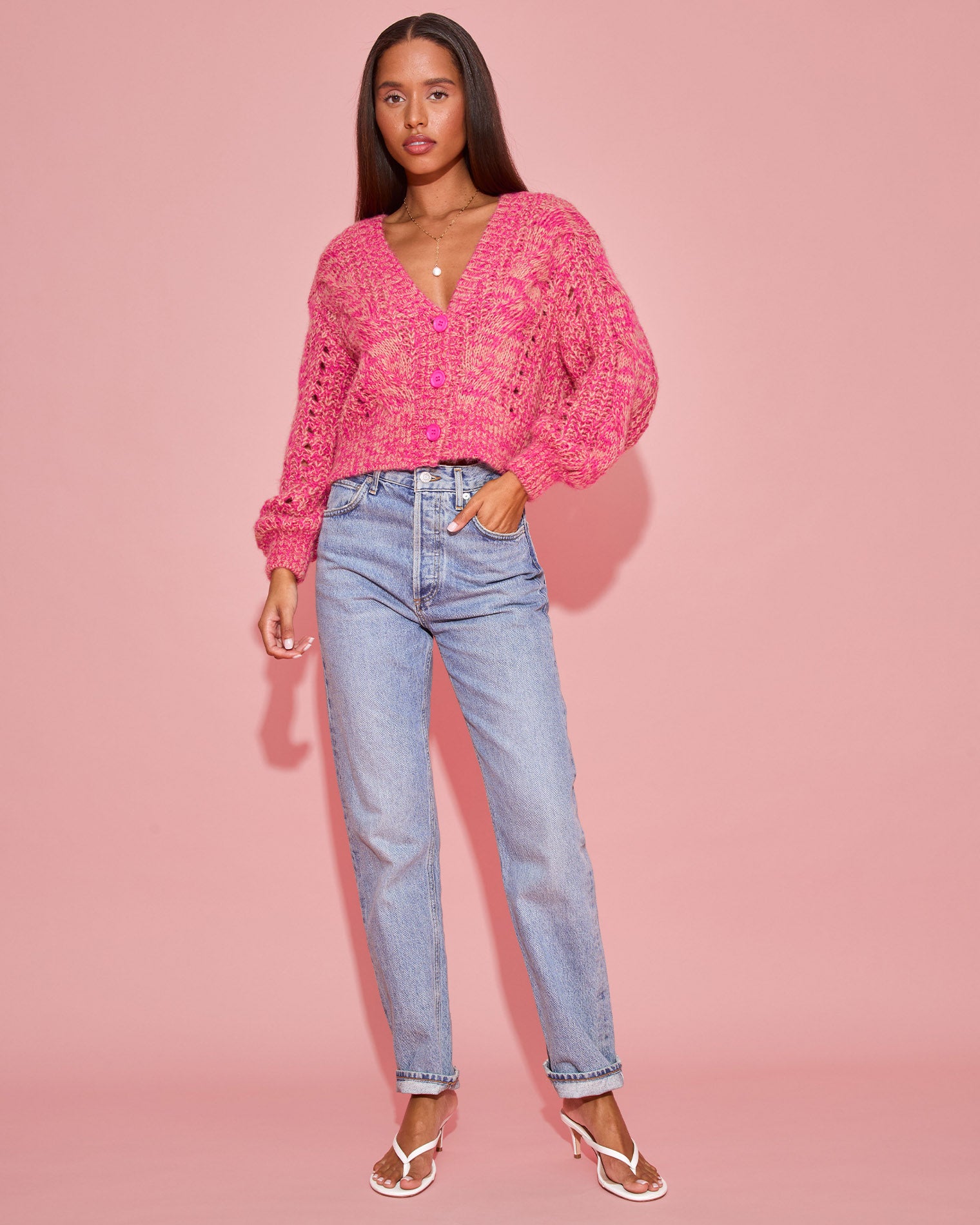 Strawberry Fields Cardigan - Strawberry Marl Full-length front view of a model wearing the LSPACE Strawberry Fields Cardigan in strawberry marl, styled open over a white tee with jeans and white strappy sandals on a pink background.