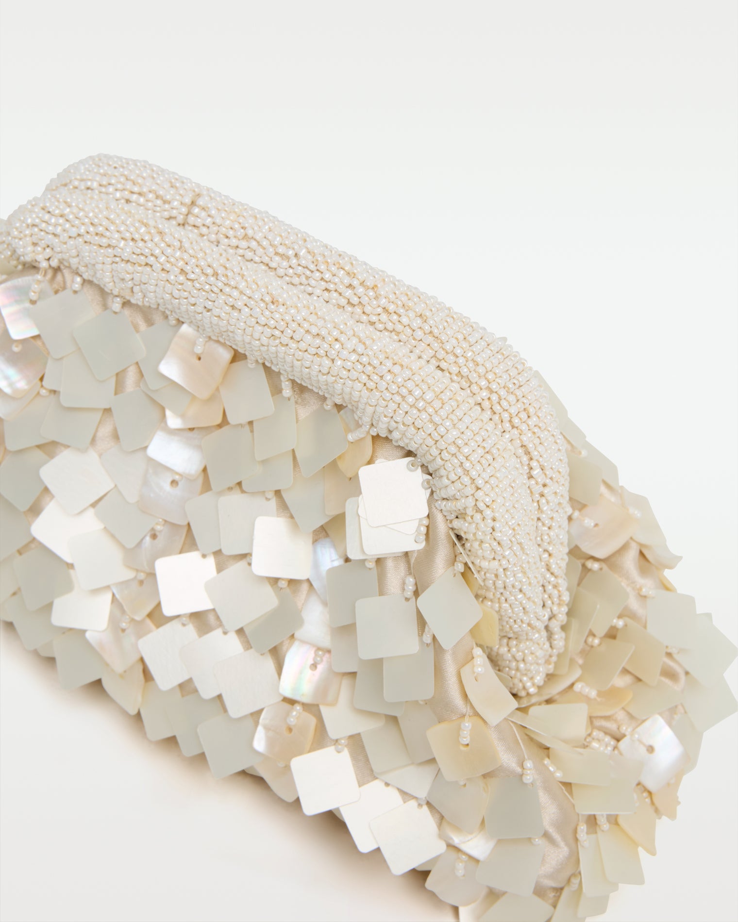 Vienna Clutch - Cream Close-up detail of the Vienna Clutch in cream showing the beaded frame clasp and the layered iridescent mother-of-pearl shell tile paillettes.