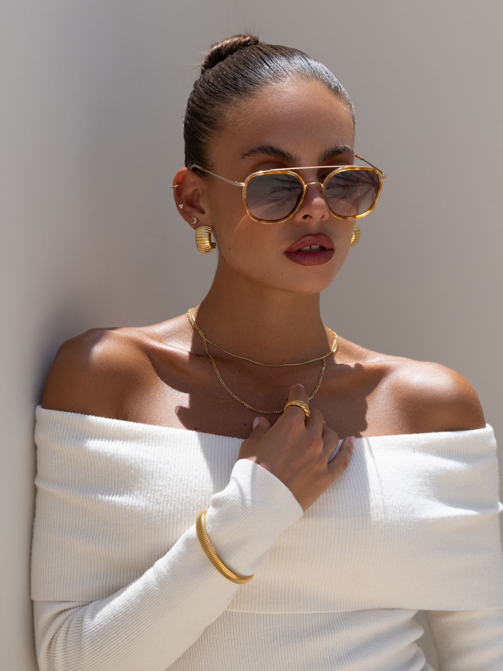 Freyrs Weston Sunglasses - Light Tortoise Model wearing the Freyrs Weston Sunglasses in light tortoise, dressed in a white off-shoulder top with gold jewelry.