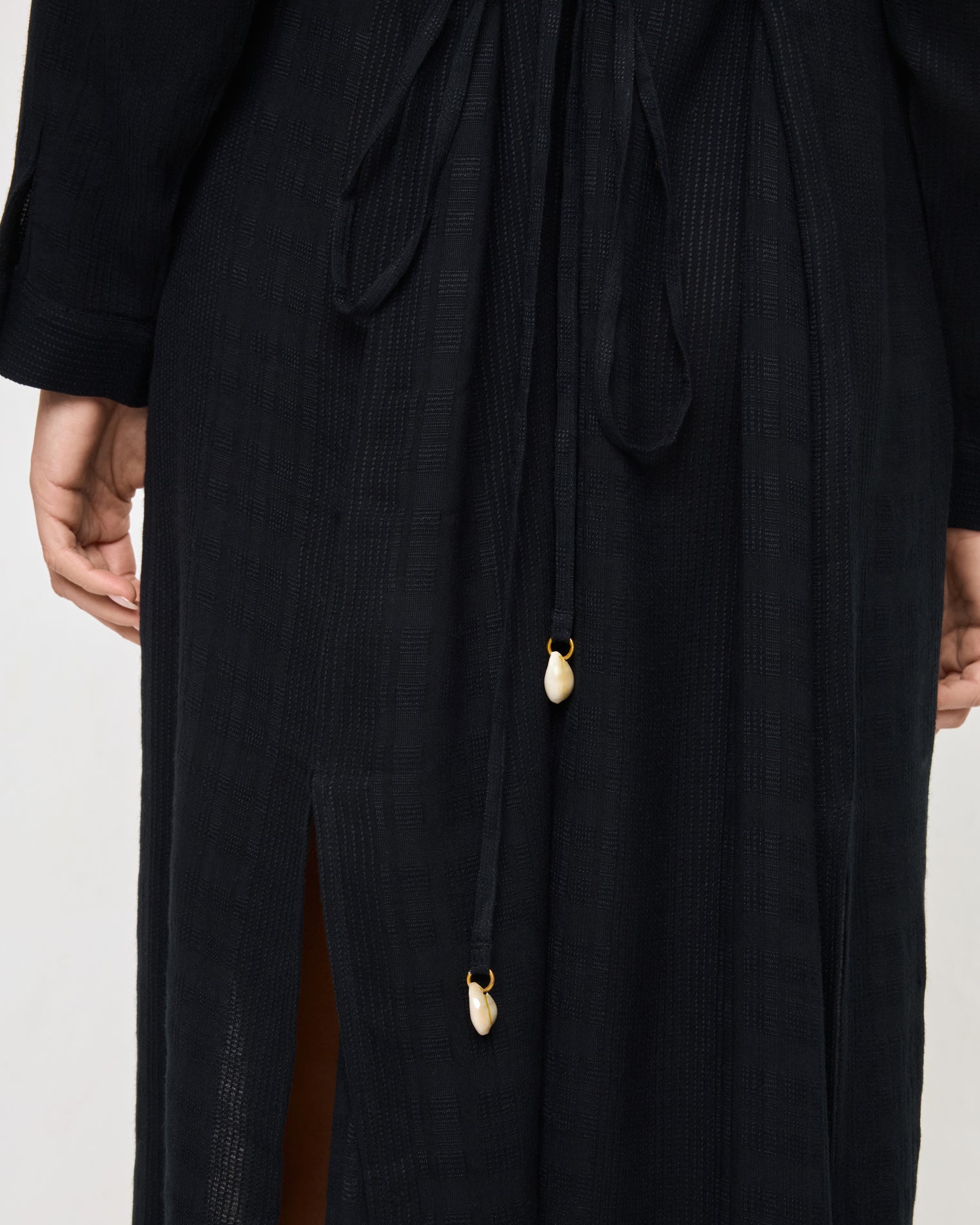 Yoli Shirtdress - Black Close-up of the LSPACE Yoli Shirtdress in black, highlighting the drawstring waist tie with decorative cowrie shell charm accents.