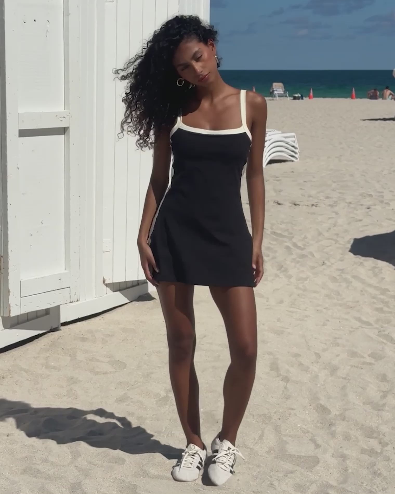 Nikki Dress - Black-Cream Video of model wearing the Nikki Dress in black-cream posing in front of the beach.