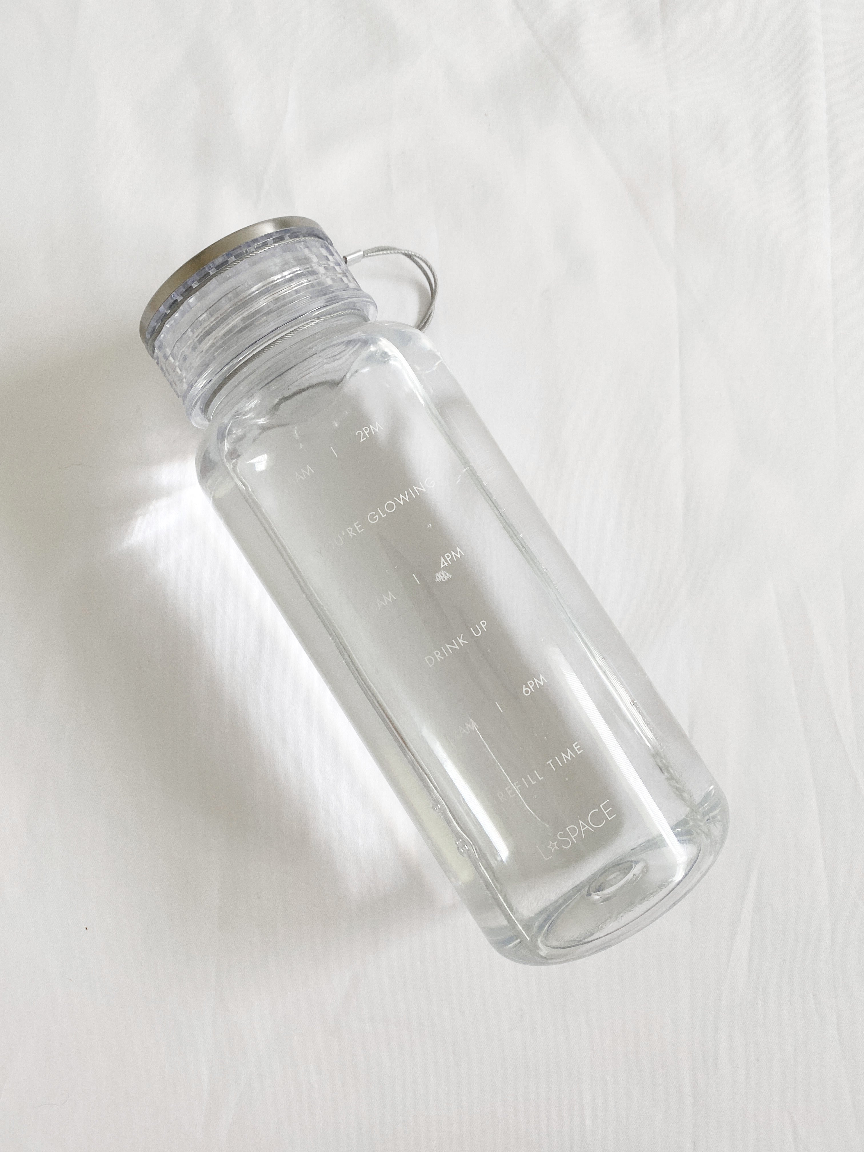 LSPACE water bottle with wellness quotes, off-model flat lay.