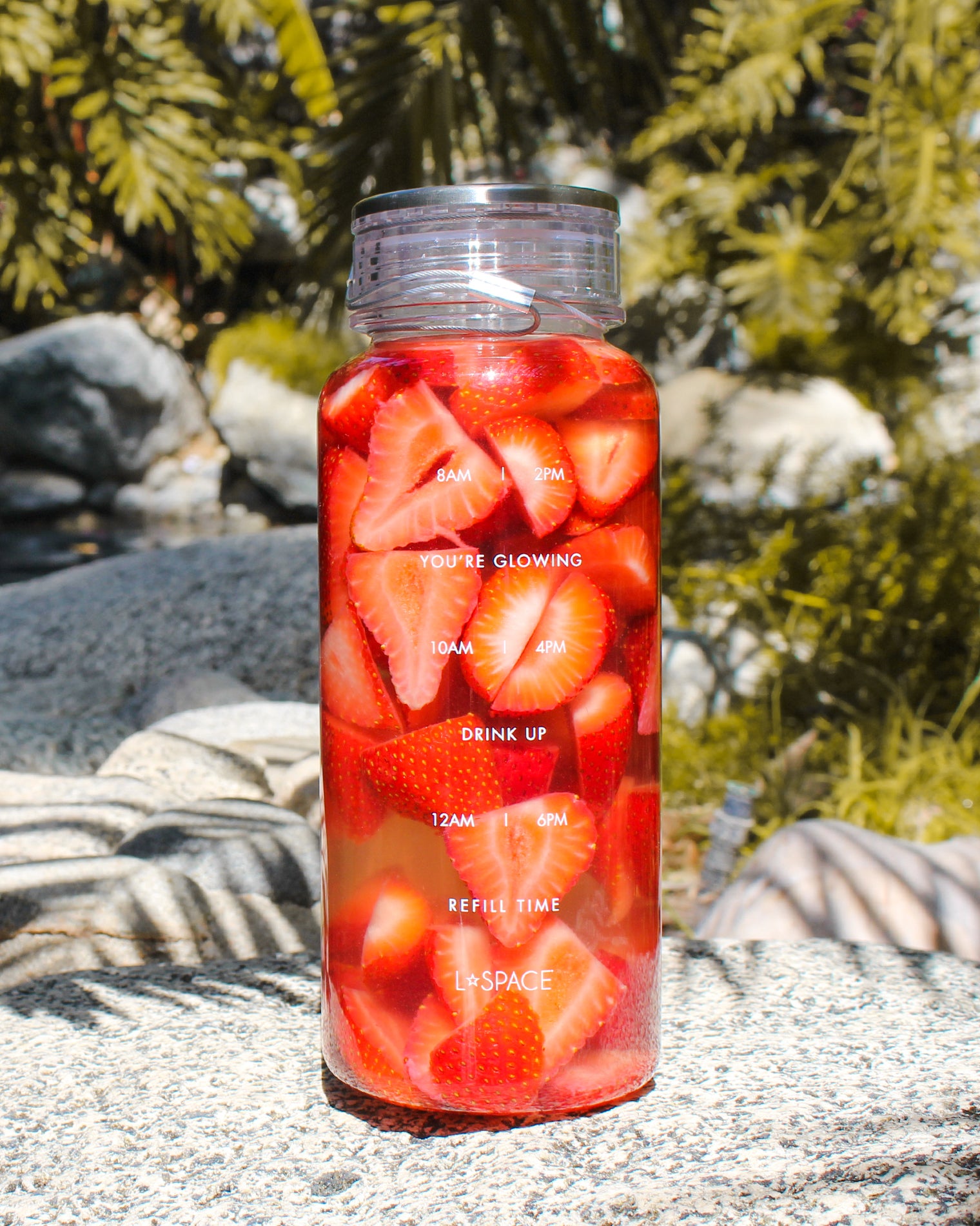 LSPACE Water Bottle LSPACE water bottle filled with sliced strawberries, off-model lifestyle shot outdoors.