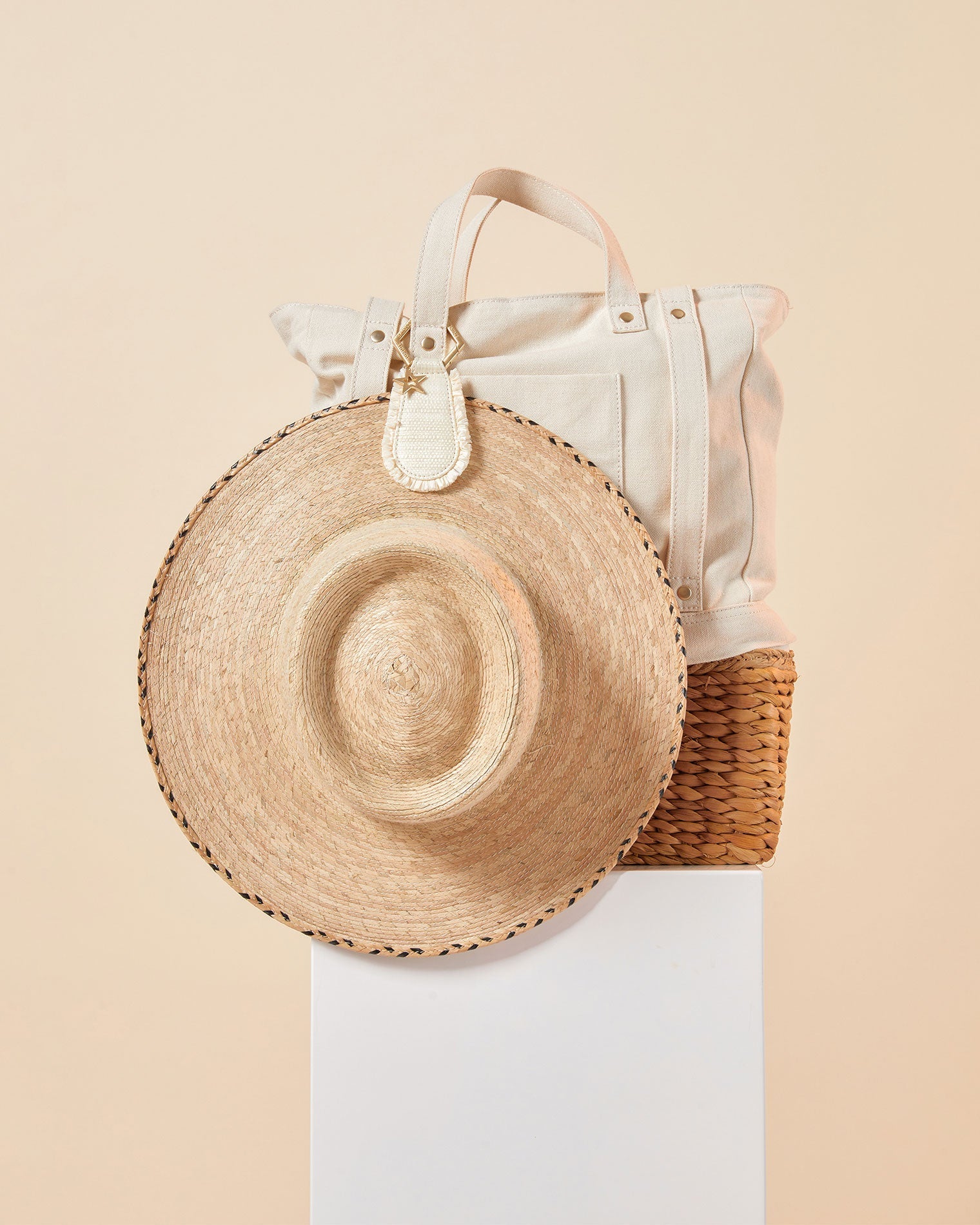 LSPACE x Lindsay Albanese TOPTOTE - Tobacco Off-model image of the LSPACE x Lindsay Albanese TOPTOTE in a natural colorway clipped to a canvas tote bag alongside a straw hat on a white pedestal.